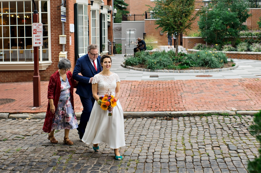 A bride and her parents cross the cobblestone street going to her ceremony at the Shambles in Philly.